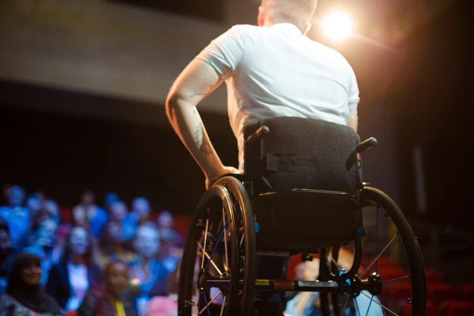 En mann i rullestol foran et publikum.