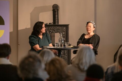 To kvinner sitter ved et bord foran et publikum.