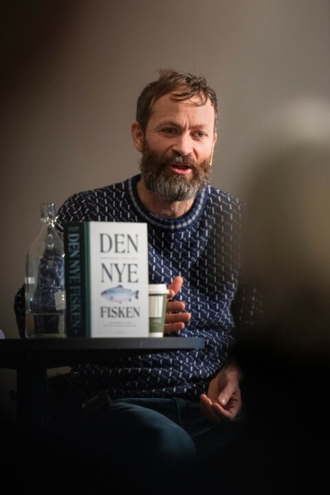 En mann som sitter ved et bord med en bok foran seg.