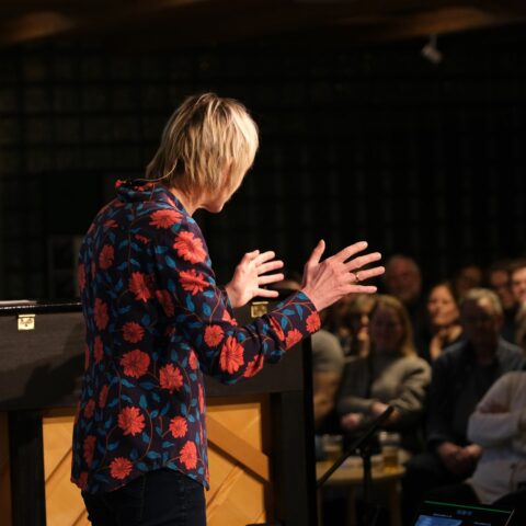 En kvinne holder en tale foran et publikum.