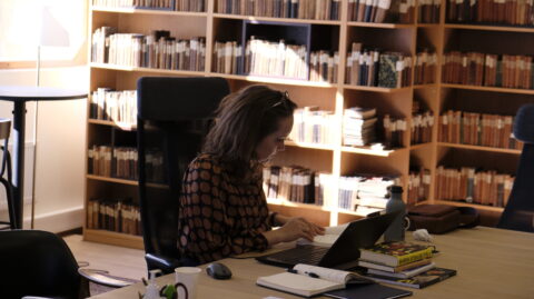 En kvinne som jobber på en bærbar datamaskin i et bibliotek.